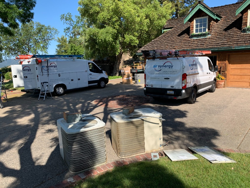 Two Air Synergy branded service vans on-site at a Bay Area property, ready to install and service HVAC equipment