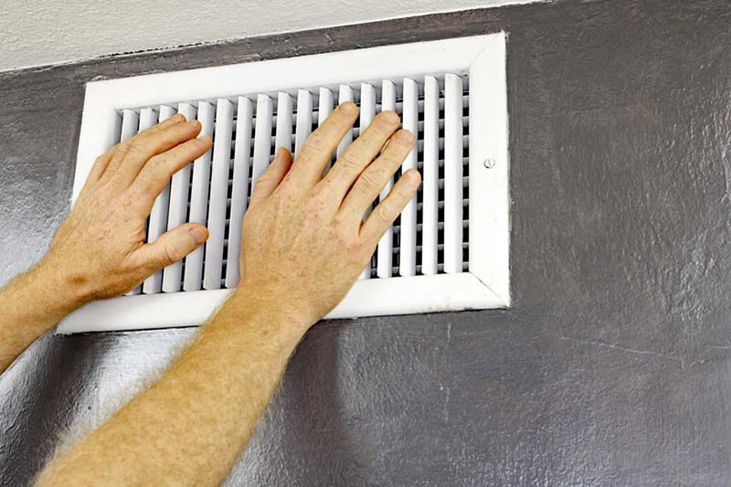 a pair of male adult hands feeling the air flow from an ac vent, ac blowing hot air