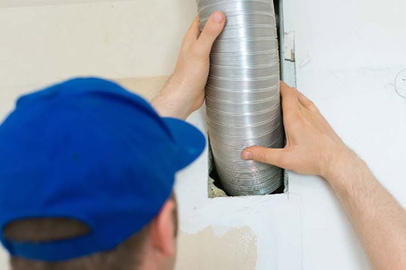 Man setting up ventilation system indoors.