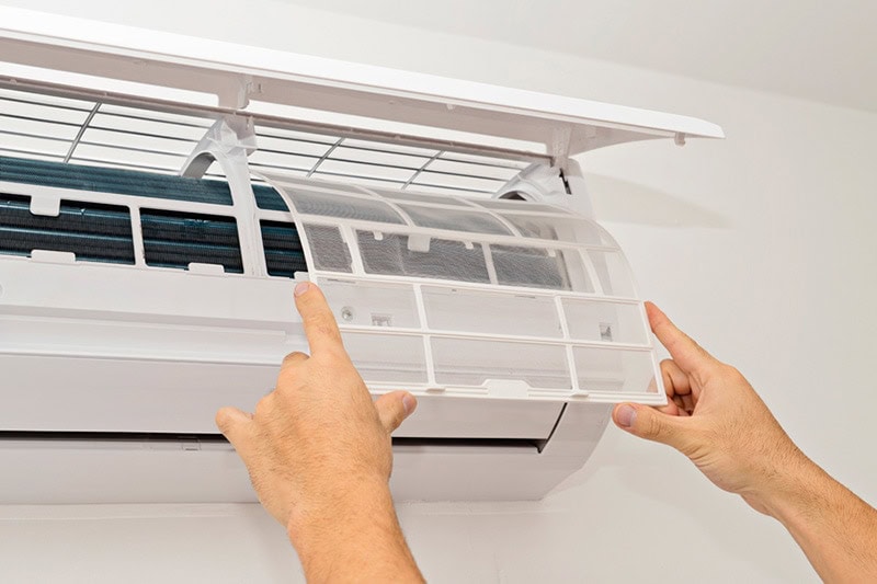 What Maintenance Is Needed for a Ductless System? Person working on ductless air conditioning unit.