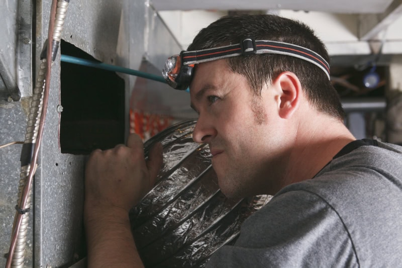 HVAC technician performing maintenance on furnace.