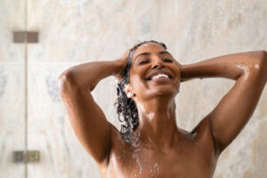 African woman washing hair under shower.